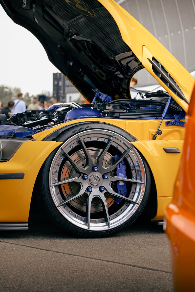 A detailed shot of a yellow supercar with its hood open showcasing the wheel and engine details.